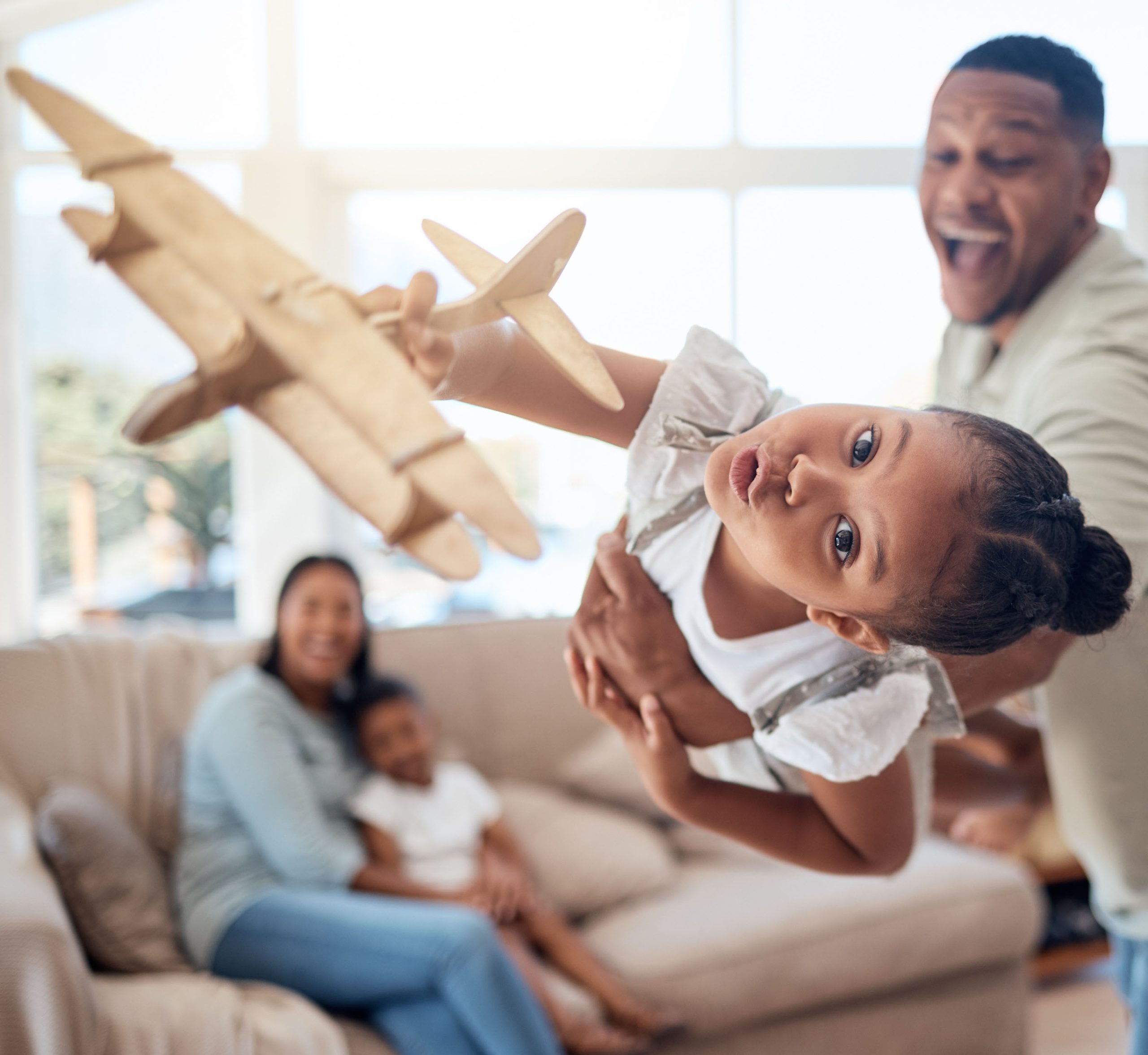 Father, girl or playing with toy airplane in family home or house living room for exciting game, travel dreams or fantasy. Playful portrait, plane or fun child bonding with man, dad or lifting parent.